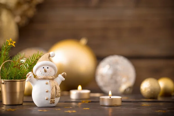 Christmas golden decorations and snowman on dark wooden background