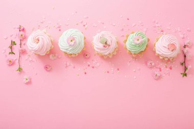 Pembe arka planda bahar çiçekleri olan pembe ve yeşil kekler.
