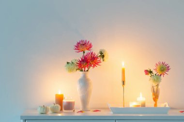 Çiçekleri, balkabakları, beyaz arka planda mumları olan güzel bir dekor.