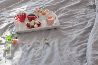 Yatakta iki kırmızı kahve ve çiçek.