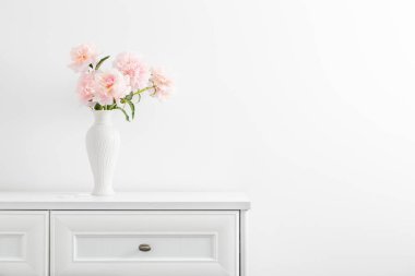 Beyaz vazoda, seramik beyaz vazoda pembe şakayıklar.