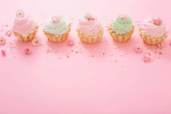 pink and green cupcakes with spring flowers  on pink  background