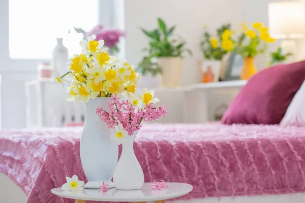 yellowand pink spring flowers in  vase in modern pink bedroom