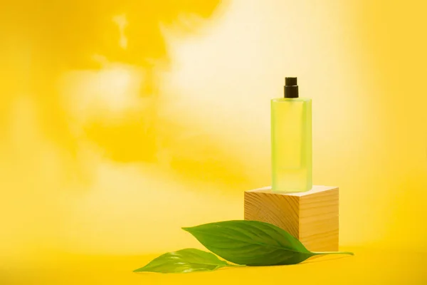 Frasco Perfume Com Folhas Verdes Sobre Fundo Amarelo — Fotografia de Stock