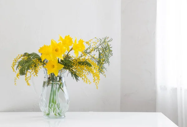 白い背景のガラス花瓶の黄色い春の花 — ストック写真