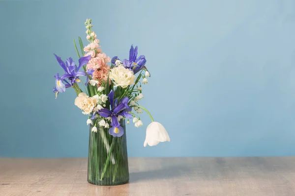 spring flowers in glass vase on blue background