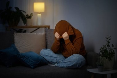 Üzgün genç geceleri kanepede oturuyor.