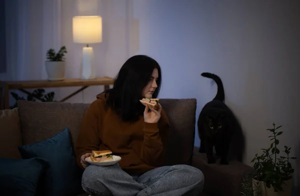 Έφηβος Κορίτσι Τρώει Σάντουιτς Γάτα Βράδυ Στον Καναπέ — Φωτογραφία Αρχείου