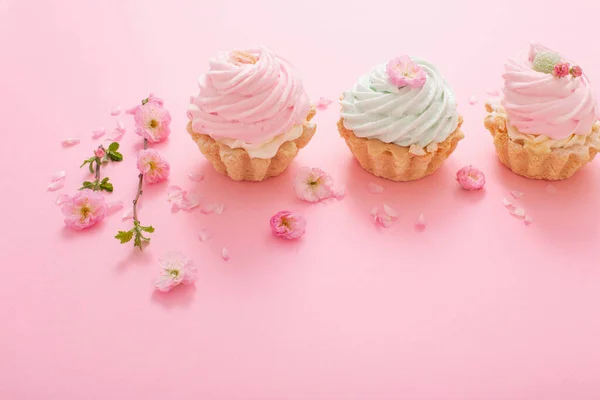 pink and green cupcakes with spring flowers  on pink  background