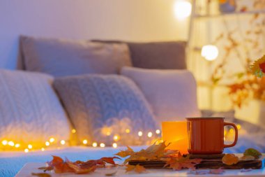 Bir fincan çay ve sıcak iç kısımda sonbahar yaprakları.