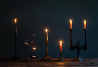 Koyu arkaplanda eski şamdanlarla mum yakmak