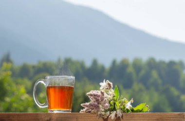 Güneş ışığında arka plandaki dağlarda bir fincan çay.