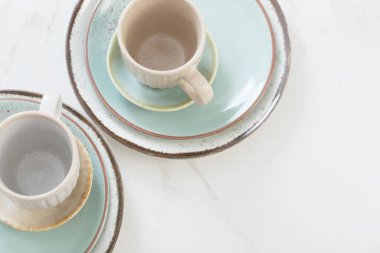 Beyaz mermer masada iki seramik bardak ve tabak.