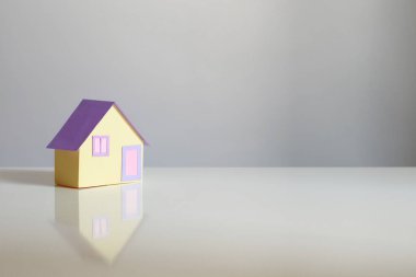Gri arka planda küçük kağıt ev