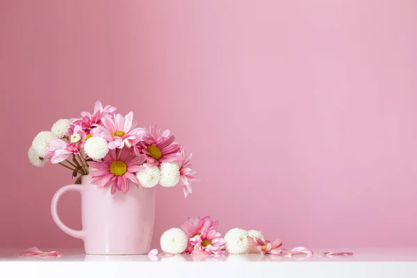 white and pink  chrysanthemums in pink cup on pink  background