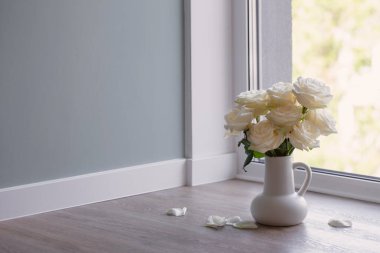 Modern iç mekanda beyaz sürahide bir buket gül