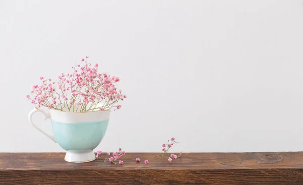 白い背景の木の棚の上の青いカップにピンクのジプシーの花 — ストック写真