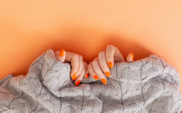 オレンジ色のマニキュアを持つ女性の手は — ストック写真