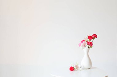 Beyaz arkaplanda beyaz vazodaki çiçekler