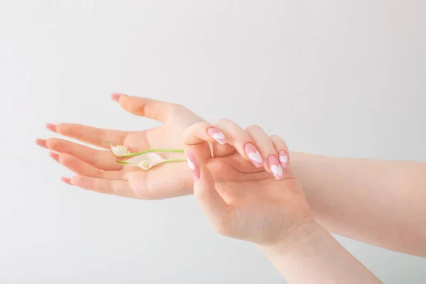 白い背景に花のある美しい長い爪を持つ女性の手 — ストック写真