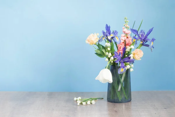 spring flowers in glass vase on blue background