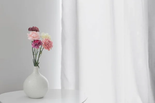 漂亮的康乃馨花在白桌子上的陶瓷花瓶里 — 图库照片