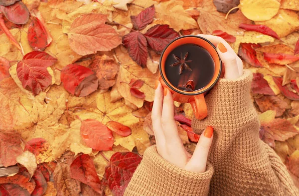 Frauenhände Mit Orangefarbener Tasse Kaffee Auf Herbstblättern — Stockfoto