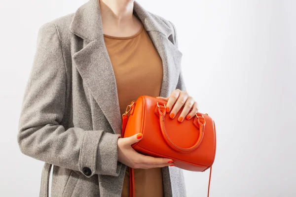 白い背景にオレンジのハンドバッグとグレーのコートの女性 — ストック写真