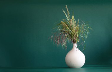 Yeşil arka planda modern vazodaki yabani ot