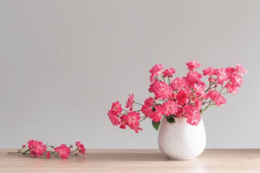 Ahşap rafta seramik vazoda pembe güller