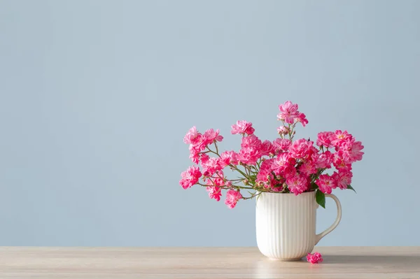 蓝色底色陶瓷花瓶中的粉红玫瑰 — 图库照片