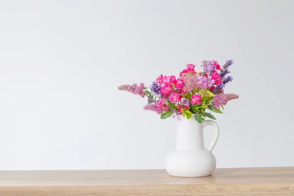 木制架子上的白色水壶中的美丽花朵 — 图库照片