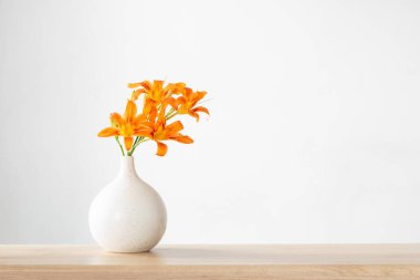 Beyaz, modern vazoda yaz çiçekleri, ahşap rafta.