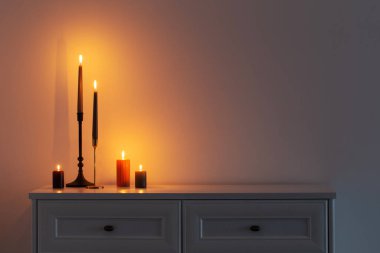 Beyaz iç kısımda, beyaz ahşap rafta mum yakmak.