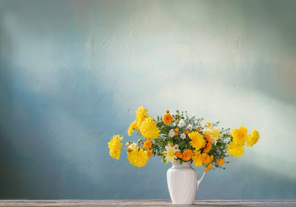木製のテーブルの上の白いジャグの黄色と白の菊 — ストック写真
