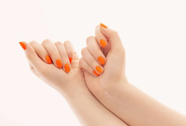 白い背景にオレンジ色のマニキュアを持つ女性の手 — ストック写真