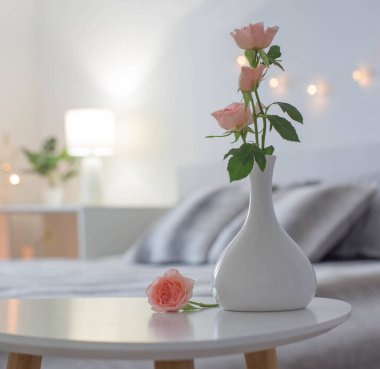 Yatak odasındaki masada vazoda pembe güller.