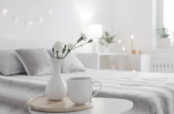 寝室のテーブルの上の花瓶にコーヒーと白い花のカップ — ストック写真