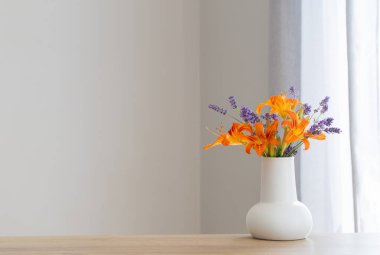 Tahta rafta beyaz sürahide yaz çiçekleri