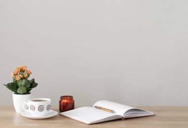 Modern iç mekanlarda ev bitkisi, not defteri, kalem ve kahve fincanı ile hayat devam ediyor.
