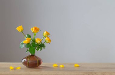 Tahta rafta beyaz sürahide sarı güller