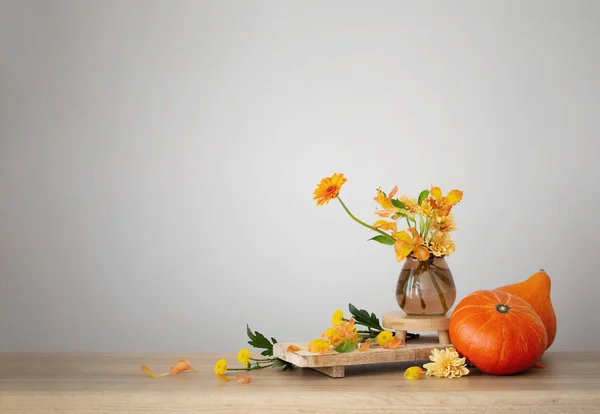 背景の灰色の壁の木の棚の秋の花束そしてオレンジのカボチャ — ストック写真