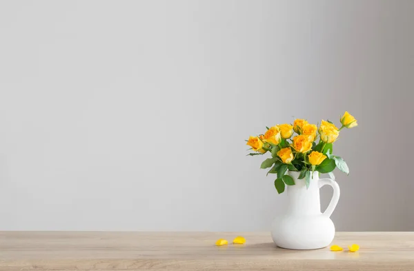 stock image yellow roses in white jug on wooden shelf