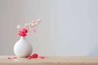 Ahşap masadaki seramik vazoda pembe güller