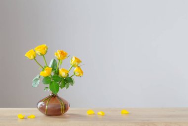 Tahta rafta beyaz sürahide sarı güller