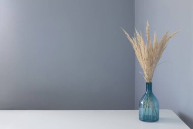 Beyaz masadaki cam vazoda kurutulmuş sarı dekoratif tahıllar.