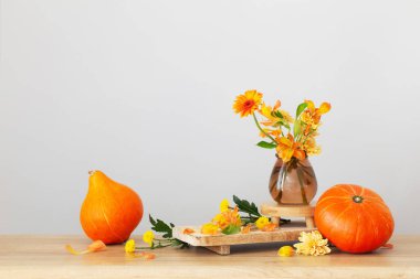 Güz buketi ve turuncu balkabakları arka plandaki ahşap rafta gri duvarda