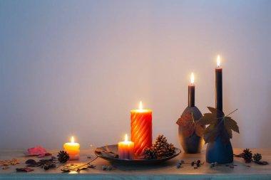 Arka plandaki ahşap rafta mumlar olan sonbahar karanlık dekoru