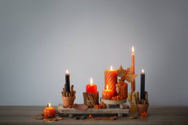 Ahşap rafta yanan mumlarla sonbahar dekoru