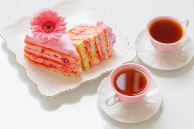 iki fincan çay ve beyaz masada pembe kek.